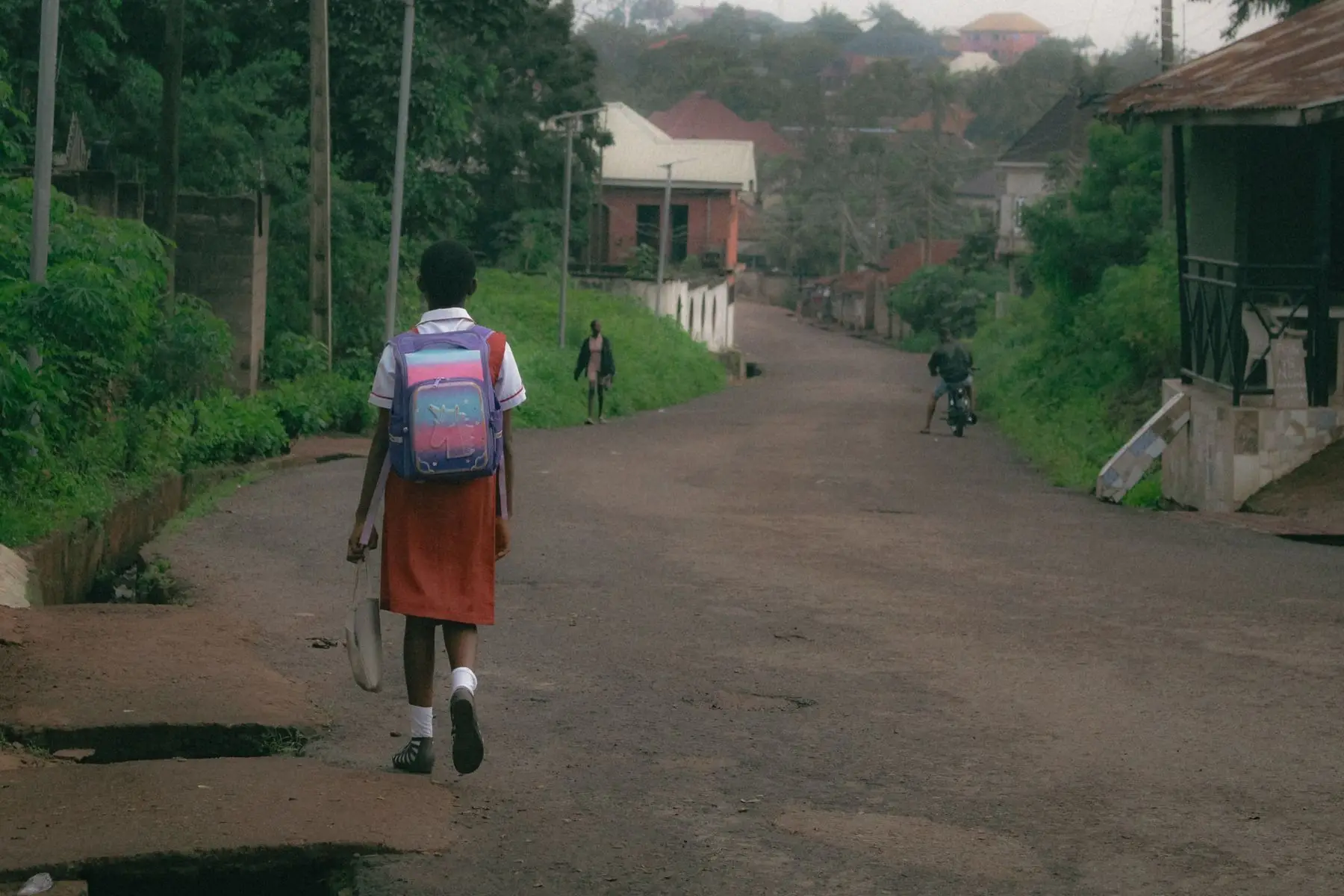 A learner walking a long open road towards school