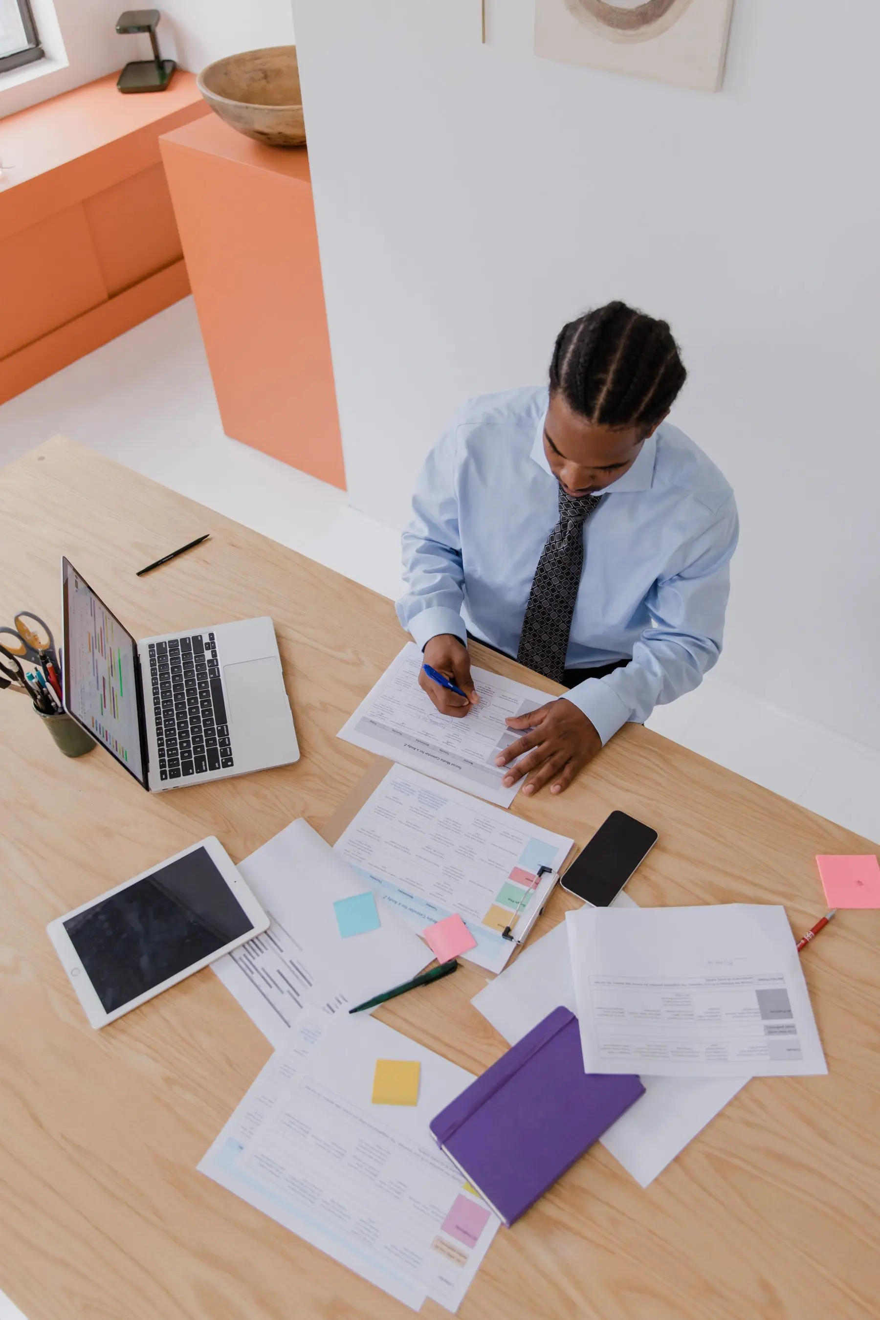 A school administrator working at a laptop with forms and notes laid out on the desk