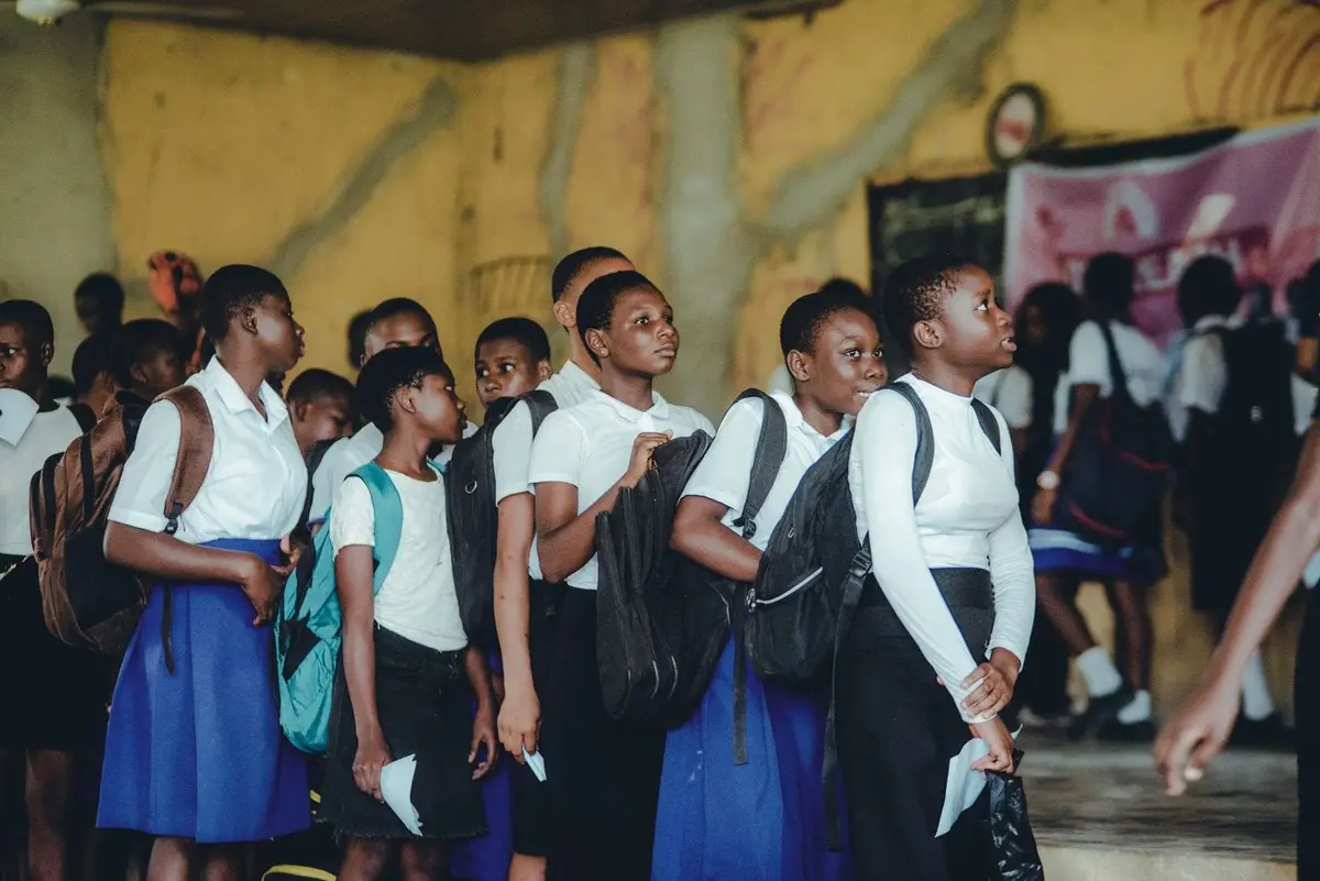 Learners in school uniform with backpacks standing together in a school hall