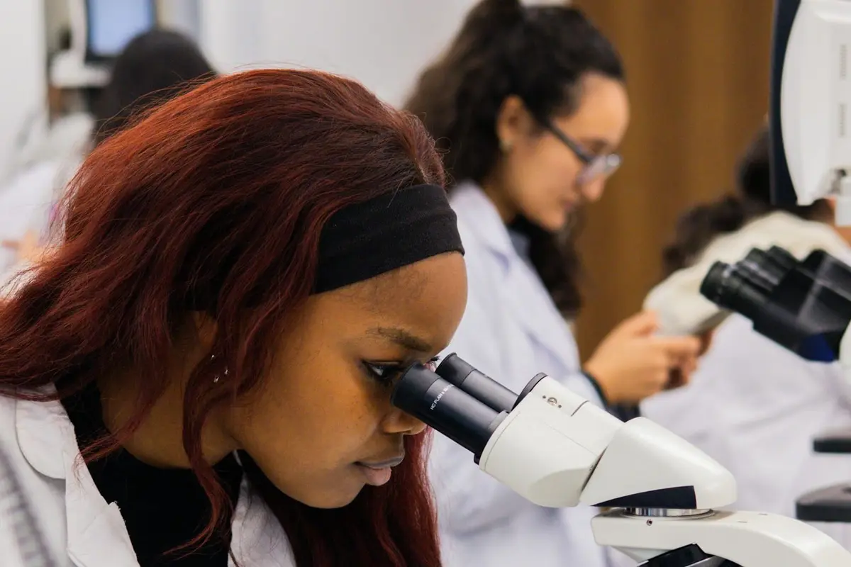 A young woman looking into a microscope in a school science laboratory