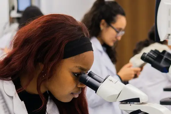 A young woman looking into a microscope in a school science laboratory