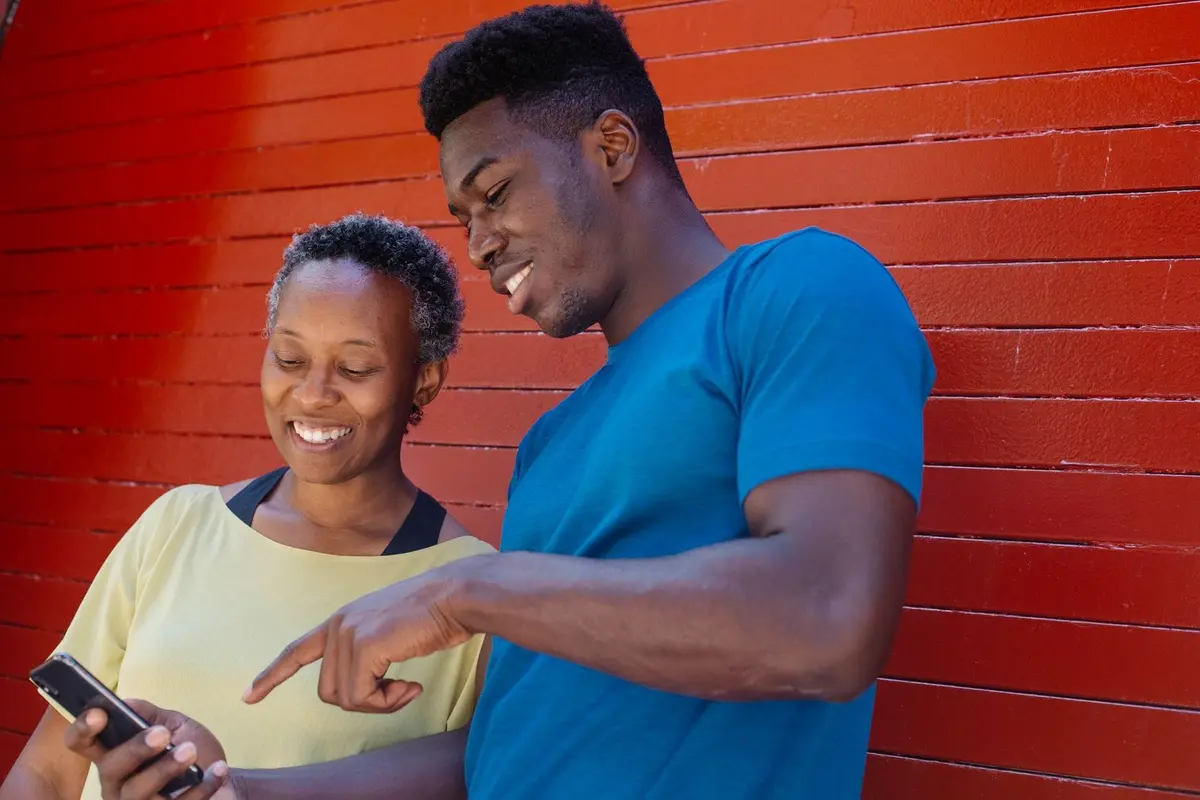 A woman and a man smiling as the man points at a phone