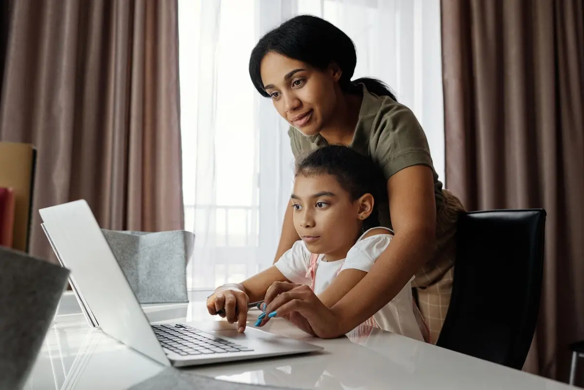 A mother and her daughter looking at a laptop together